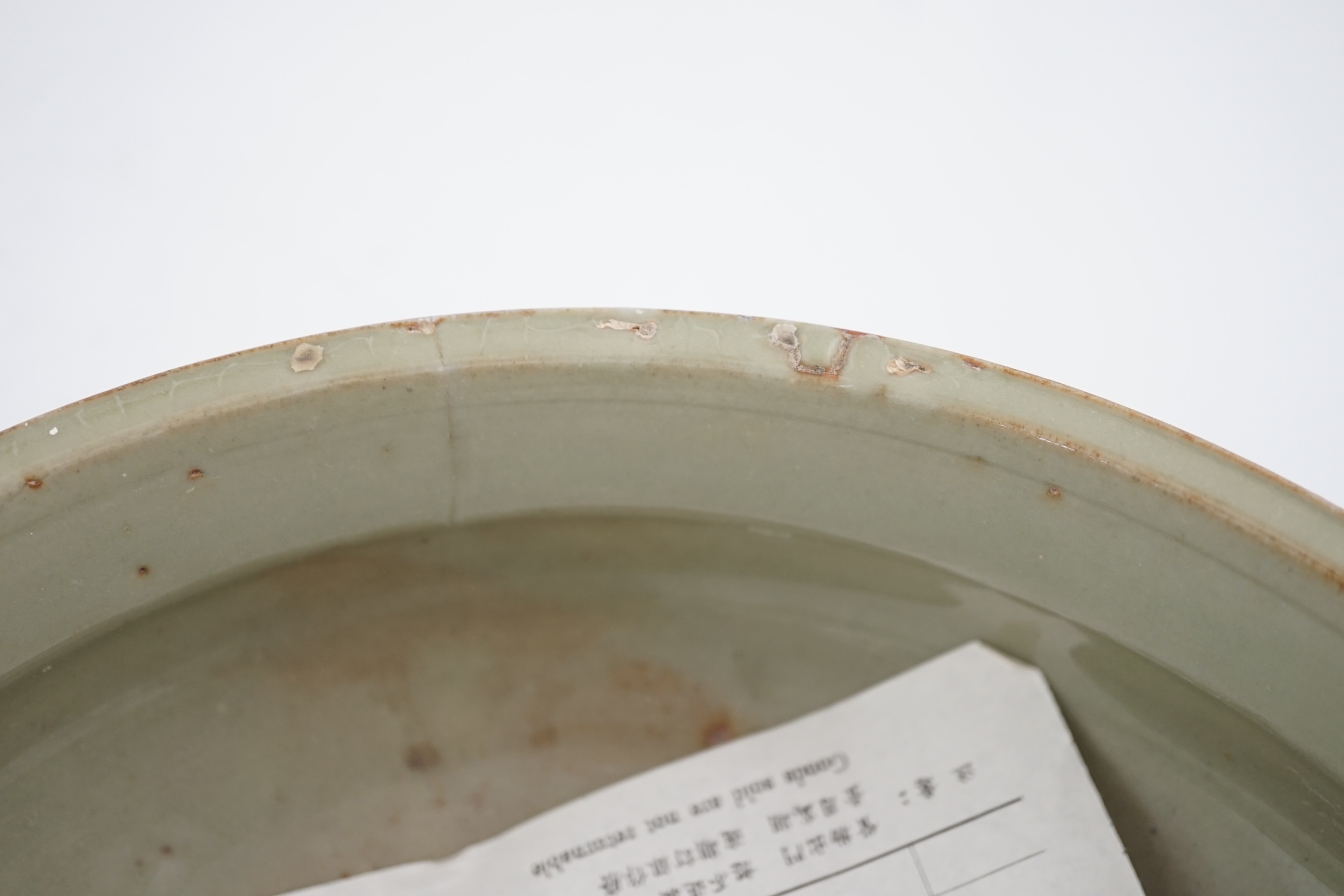 A Chinese Ming Longquan celadon tripod censer, 14th/15th century, the exterior incised with scrolling foliage, on three animal mask feet, burnt orange ring to base, 26.7cm diameter, original receipt for Wing Kei curios,
